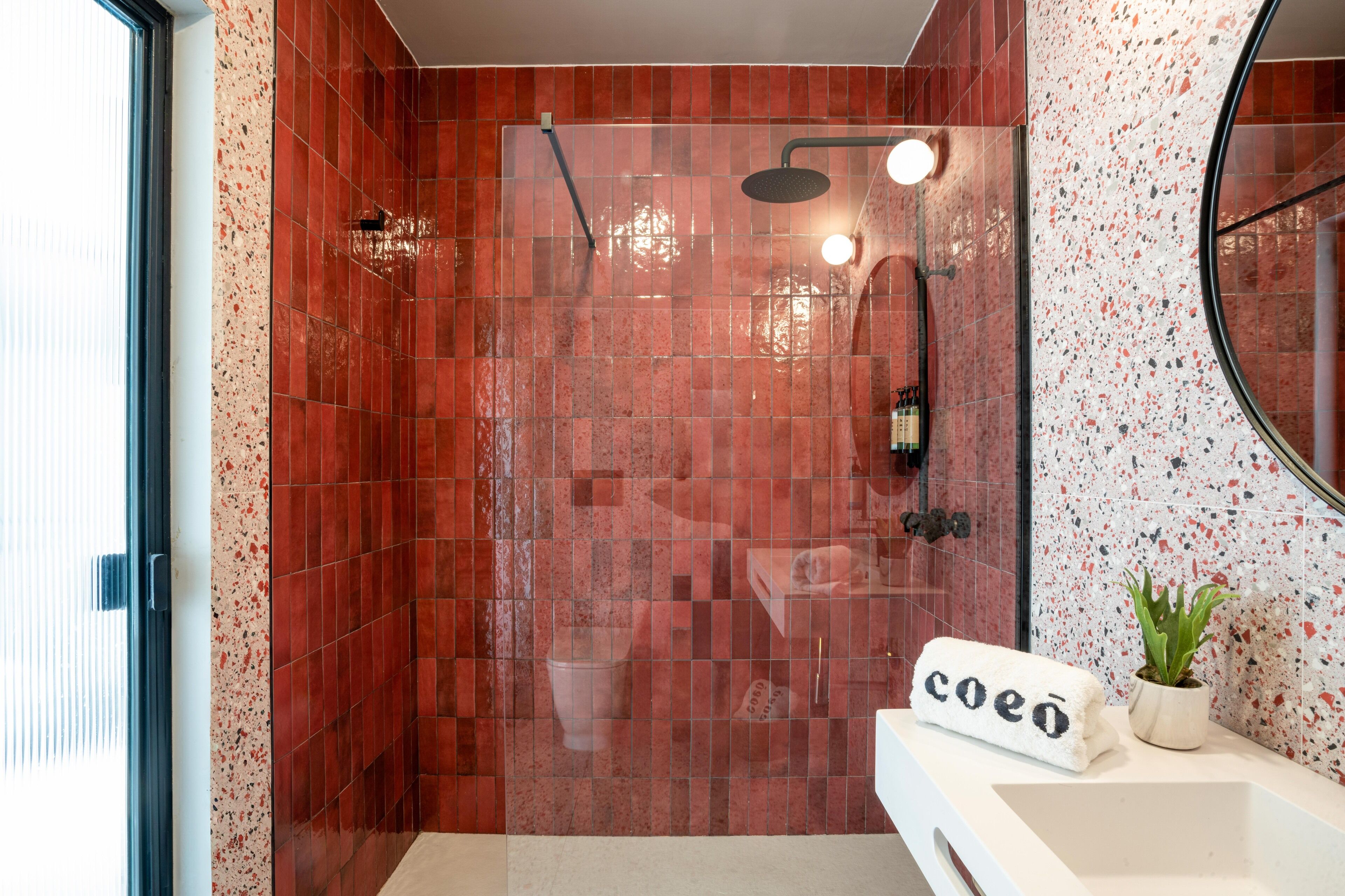 A bathroom with a shower, a sink, and a mirror.