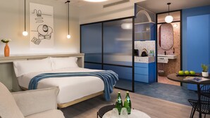 Ein modernes Hotelzimmer mit Bett, Schreibtisch und einer Küchenzeile.