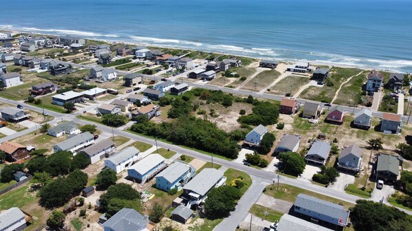Vista aérea de una zona residencial costera con casas, caminos y una playa.