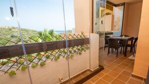 Un balcon avec vue sur la mer, un coin repas avec des chaises et une porte vitrée donnant sur l’intérieur.