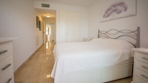 Une chambre à coucher avec un lit, une commode, une table de chevet et un tableau accroché au mur.