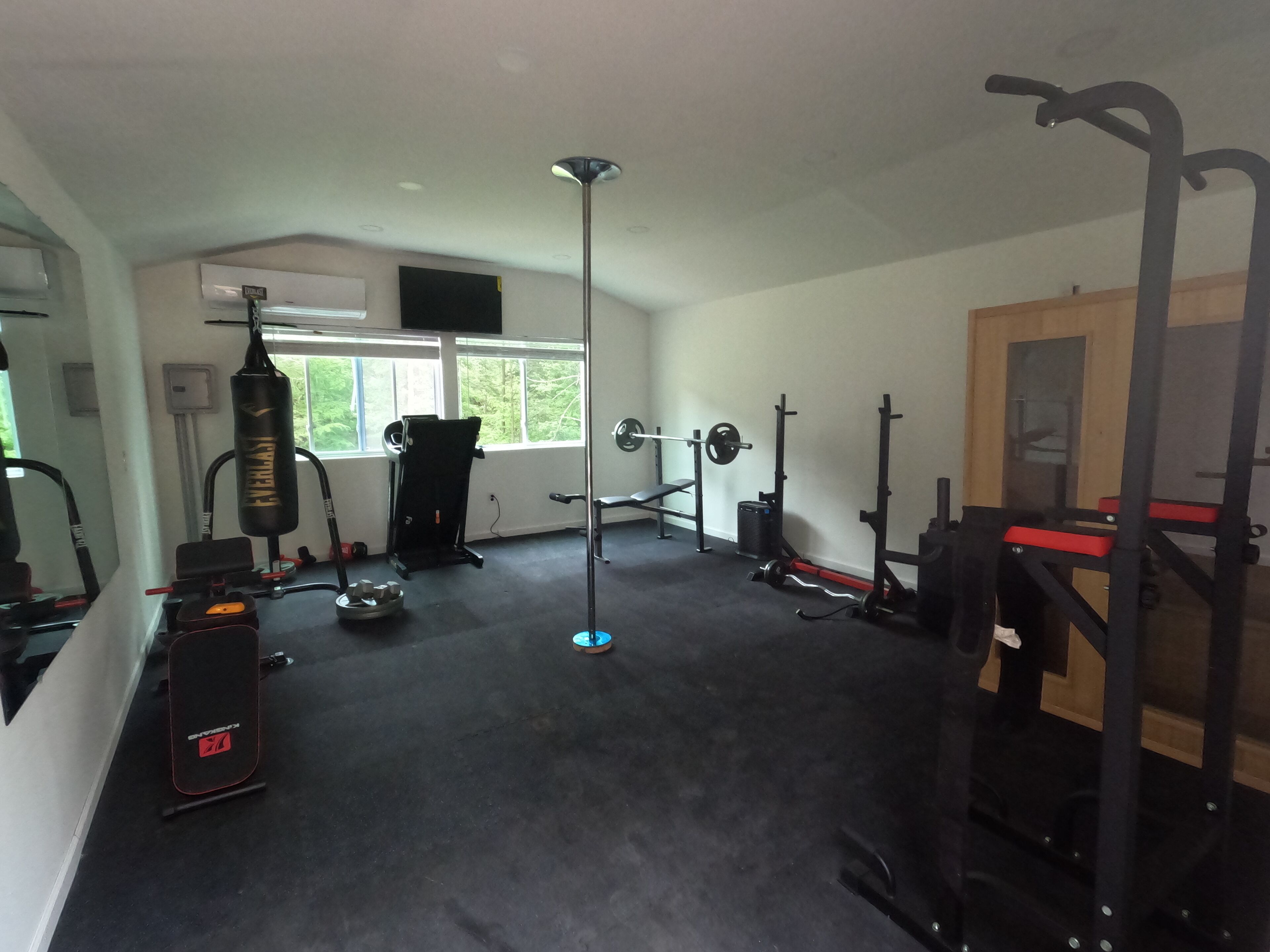 A gym with various exercise equipment, a punching bag, and a window providing natural light.