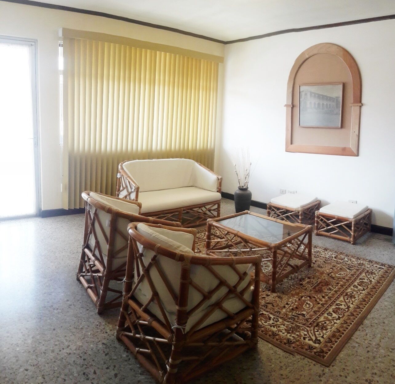 Une pièce comprenant un canapé, deux fauteuils, une table basse et un tapis à motifs.
