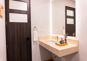 Une salle de bain avec une porte en bois foncé, un lavabo beige avec un miroir et une serviette accrochée au mur.