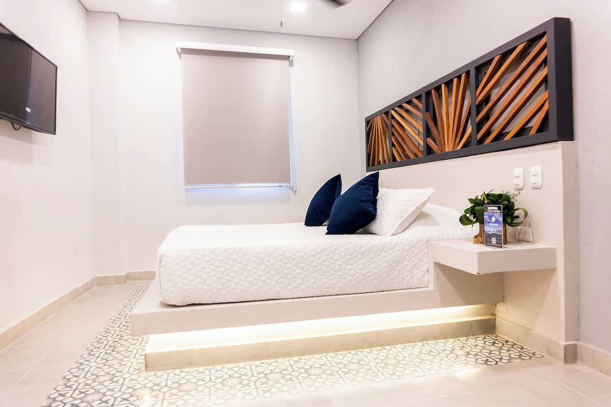 Une chambre à coucher comprenant un lit, une télévision, une fenêtre et un élément décoratif mural.