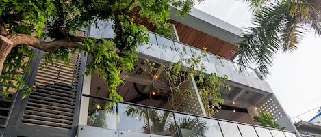 A modern building with a glass balcony, metal railings, and a staircase.