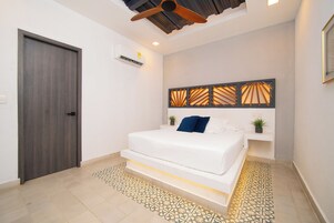 Un dormitorio con cama, ventilador de techo, equipo de aire acondicionado y piso estampado.