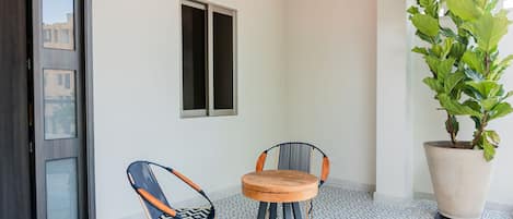 A room with a round wooden table, two chairs, a potted plant, a window, and a door.