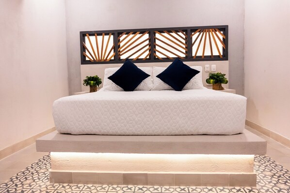 Une chambre moderne avec un grand lit, deux coussins décoratifs, une tête de lit en bois et un sol à motifs.
