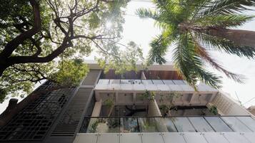 Un bâtiment moderne doté d’une façade en verre, d’un escalier en métal et entouré d’arbres.