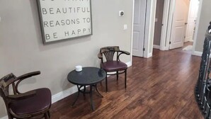 Ein Zimmer mit Holzboden, zwei Holzstühlen, einem kleinen runden Tisch und einem an der Wand befestigten Schild.
