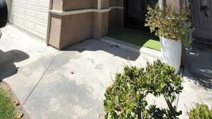 Ein zweistöckiges Haus mit Garage, einer Veranda mit Blumenbeet und einem kleinen Garten.