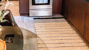 A modern kitchen with wooden cabinets, stainless steel appliances, and a patterned backsplash.