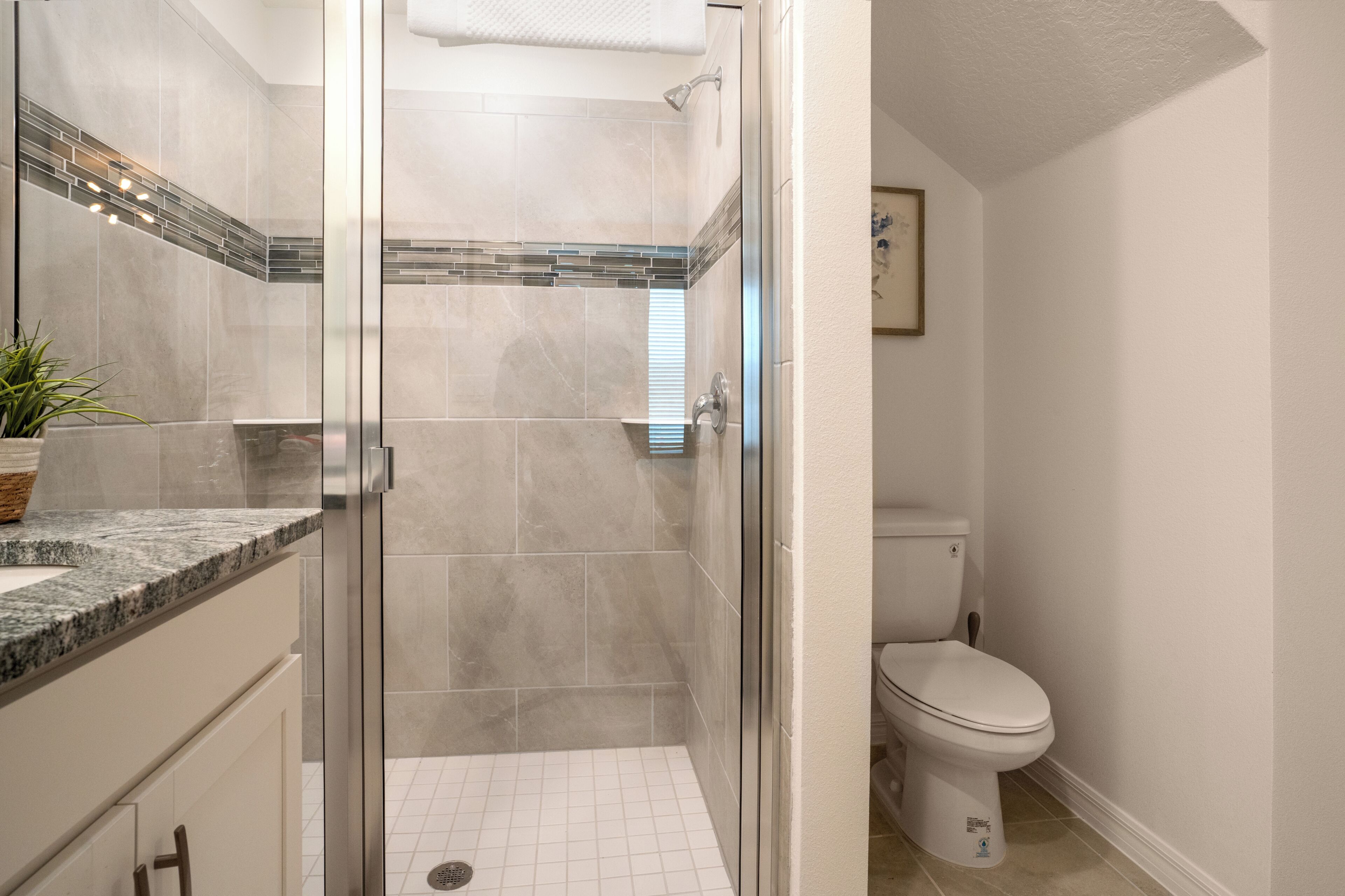 Ein Badezimmer mit einer Duschkabine, einer Toilette und einem Waschbecken mit Marmorplatte.