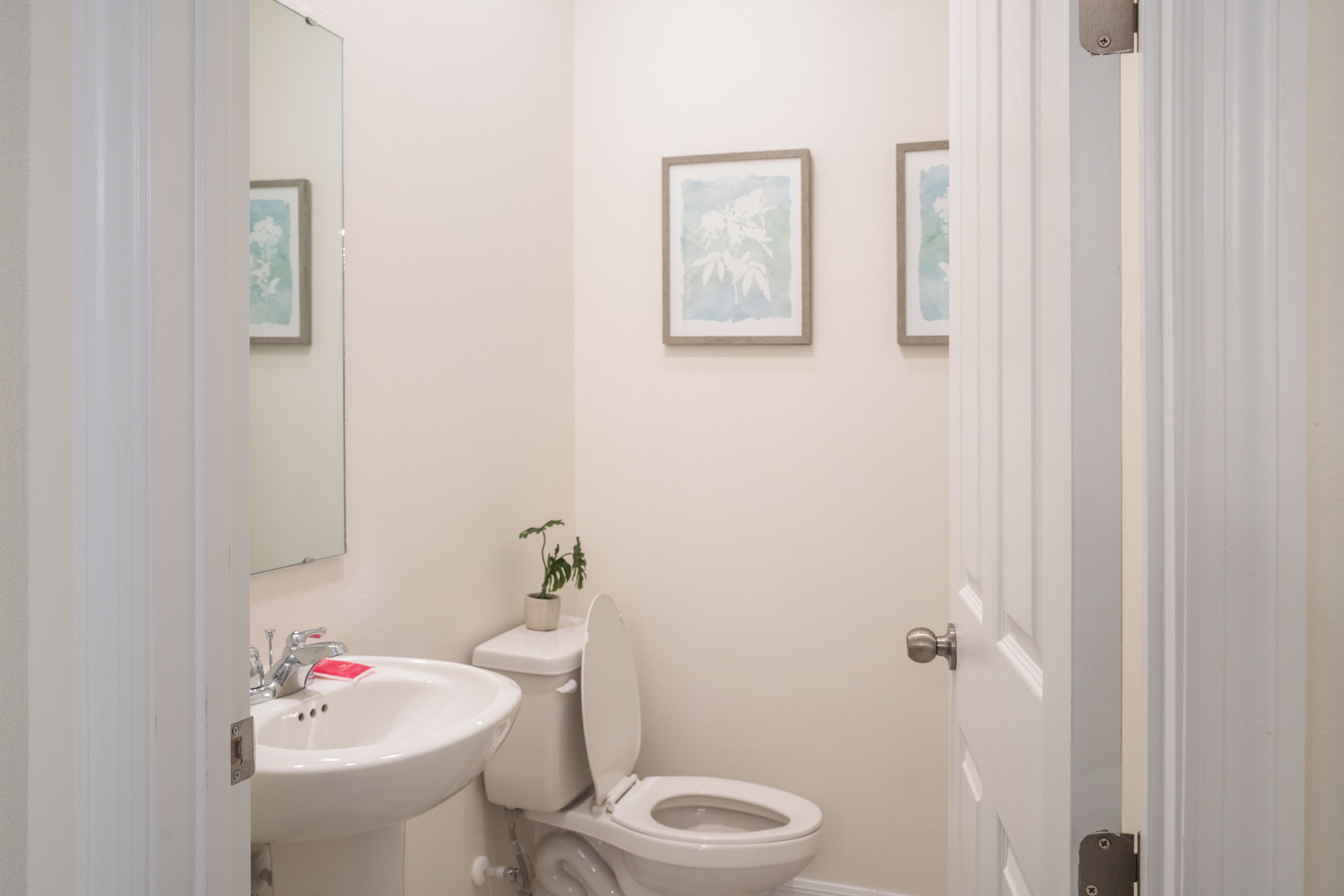 A bathroom with a sink, toilet, and framed artwork on the wall.
