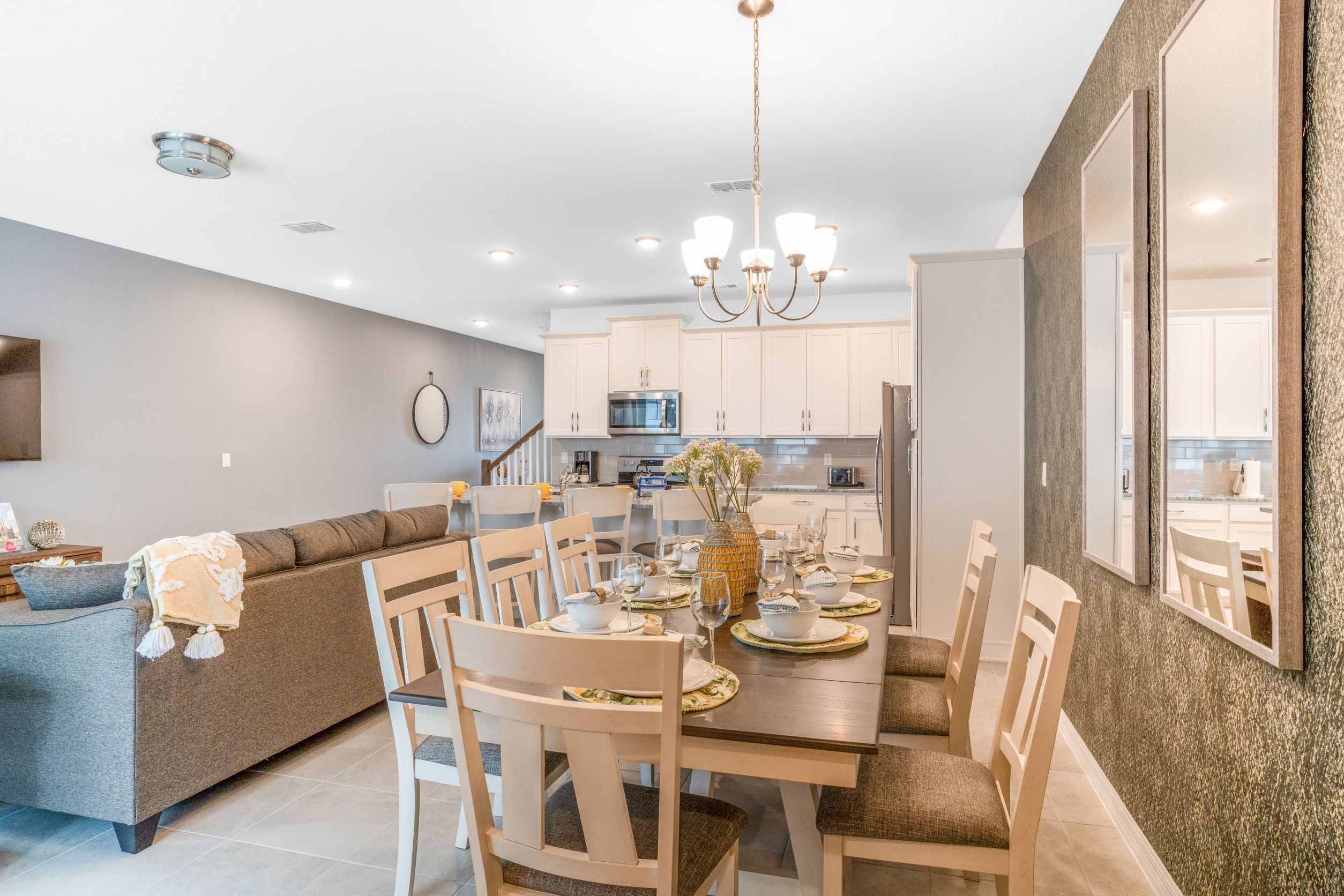 Une cuisine moderne avec des meubles blancs, un coin repas doté d’une table et de chaises en bois, et un four encastré.