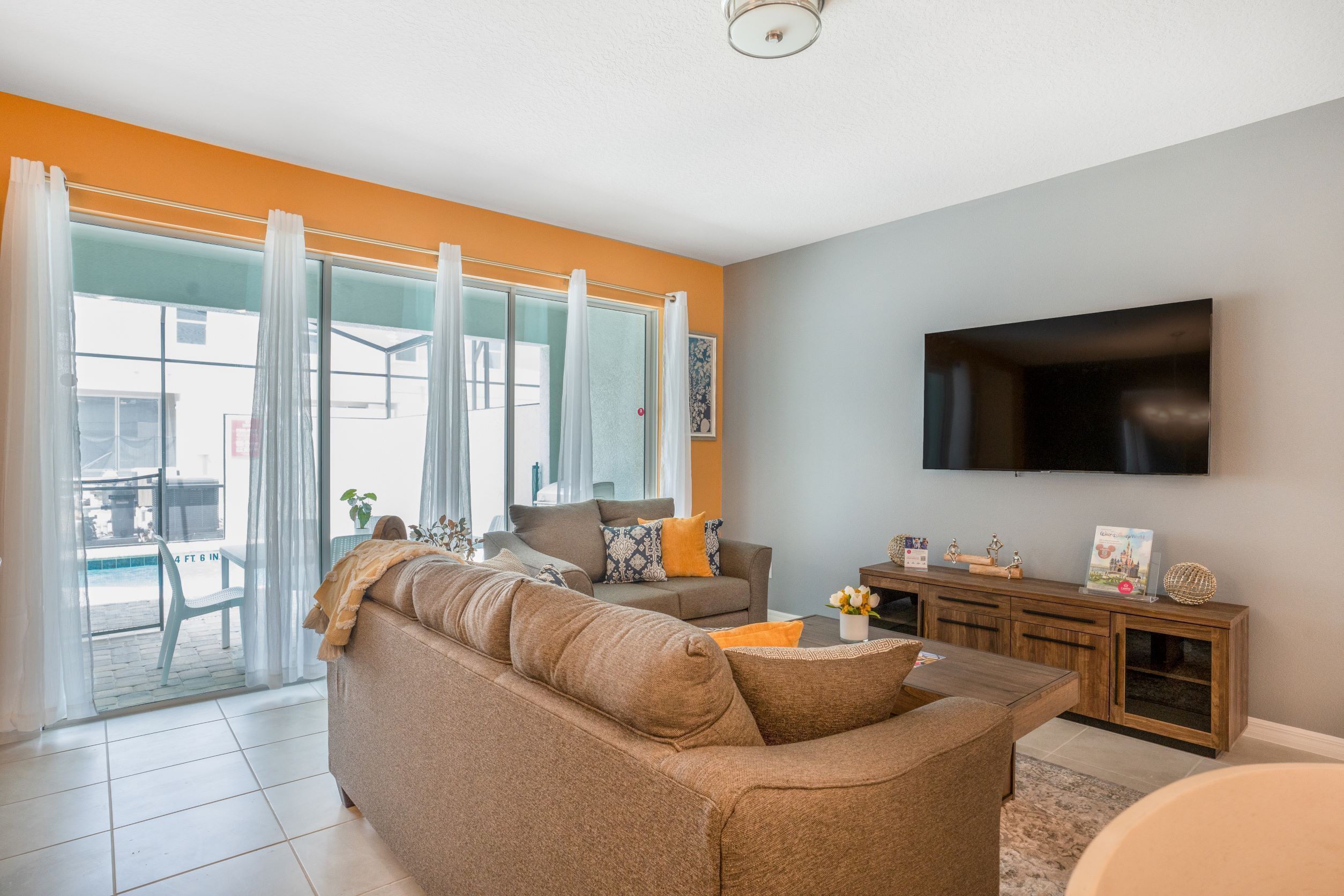 A living room with a sofa, TV, and a view through a glass door.