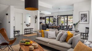 A modern living room with a sofa, coffee table, and a dining area with chairs and a table. - Luxury Villa The North Star with Pool (Okrug Gornji)