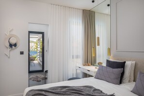 A modern bedroom with a bed, bedside table, and a view of the balcony.