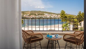 A balcony with wicker chairs, a glass table, and a view of a coastal town and sea. - Luxury Villa The North Star with Pool (Okrug Gornji)