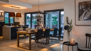 A modern dining area with a large table, chairs, and a view of the outdoors. - Luxury Villa The North Star with Pool (Okrug Gornji)