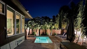 Un jardin avec une piscine, des chaises longues et une table.