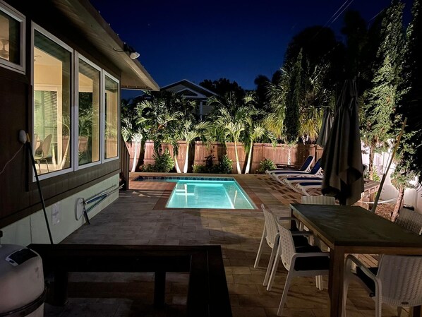 A backyard with a swimming pool, lounge chairs, and a table. - Lovely Siesta Key house near beach w/ heated pool (Siesta Key)
