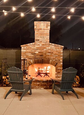An outdoor brick fireplace with two Adirondack chairs facing it, surrounded by string lights. - Stovall #2 4.5mi to Augusta National & walkable downtown! (Augusta)