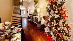 Uma sala de estar espaçosa com uma escada de madeira, uma árvore de Natal decorada e uma área de jantar com mesa posta para refeição.