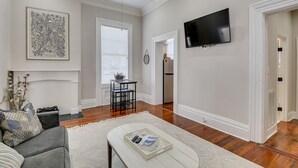 Uma sala de estar com lareira, televisão e uma área de jantar com mesa e cadeiras.
