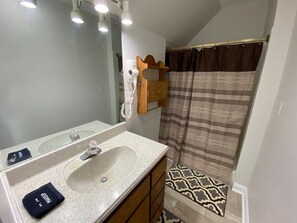Un baño con lavamanos, espejo y cortina de ducha.