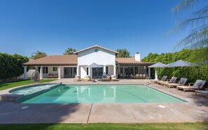 Une maison avec une piscine, un espace salon extérieur et une terrasse couverte.