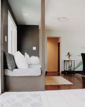 Un dormitorio moderno con cama, una mesita de noche con un florero y vistas a un pasillo.