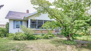 A single-story house with a front porch, a small front yard, and a tree.