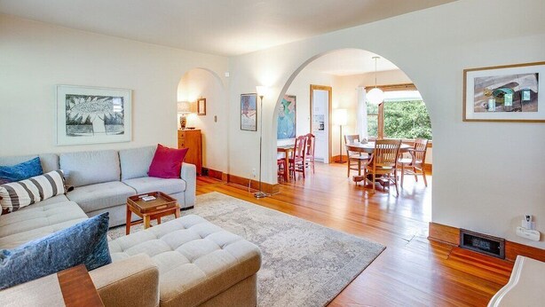 A spacious living area with a sofa, ottoman, and dining table.