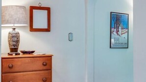 A room with a wooden dresser, a lamp, a framed picture, and a poster on the wall.