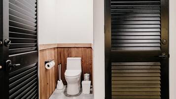 Une petite salle de bain comprenant des toilettes, un bidet et un porte-rouleau de papier toilette.