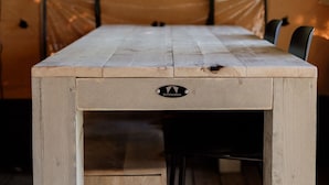 Una mesa de madera con un cajón, sobre un suelo de madera dentro de una tienda de campaña.