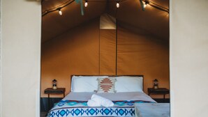 Habitació amb tenda, un llit, dues taules de nit i llums encadenades.