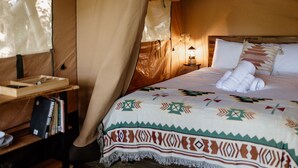 Ein gemütliches Bett mit einer gemusterten Decke, ein Nachttisch mit Büchern und ein Beistelltisch mit einer Lampe.