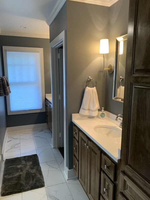 A bathroom with a white sink, dark wooden cabinets, a towel rack, and a mirror. - Great for parent weekends and orientation (Athens)