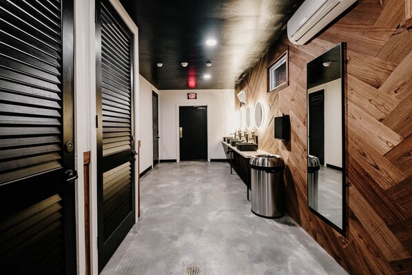 Un couloir avec un mur en bois, un coin lavabo et un panneau indiquant la sortie.