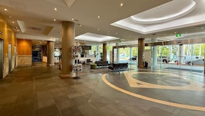 A spacious lobby with a curved seating area, a reception desk, and a large pillar. - ZEN88 Esp (408): Coastal Elegance ~ Sunset ~ Pool (Darwin City)