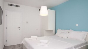 Un dormitorio moderno con una cama grande, ropa de cama blanca y una pared azul de acento.