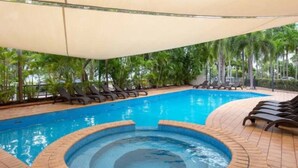 A swimming pool with lounge chairs and a covered area, surrounded by greenery. - Coastal Splendor: Seaview ~ Pool ~ Balcony Dining (Darwin City)