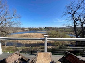 A deck with a view of a river and trees.