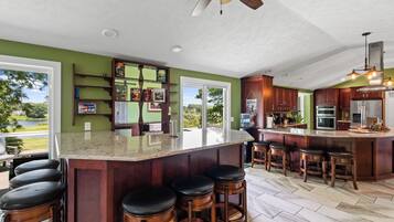 Una cocina con una isla grande, taburetes de bar y vistas al exterior.