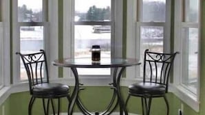 Une baie vitrée avec deux fauteuils et une table, un sol carrelé et une vue sur un paysage enneigé.