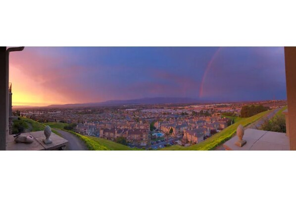 Panoramic city view from a hilltop, featuring a prominent statue.