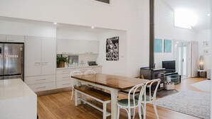 Una cocina moderna con armarios blancos, una mesa de comedor de madera y una estufa empotrada.